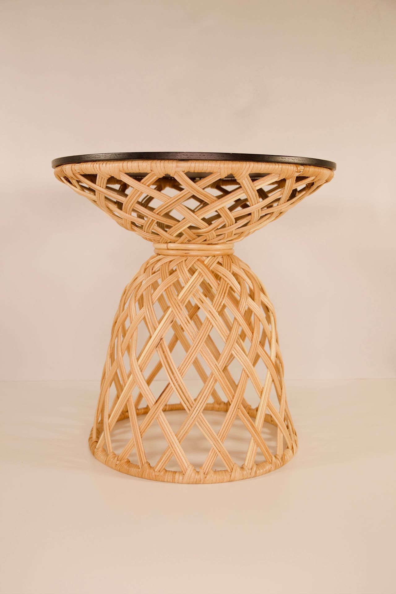 A wicker stool with a dark wooden top, featuring an intricate woven design.