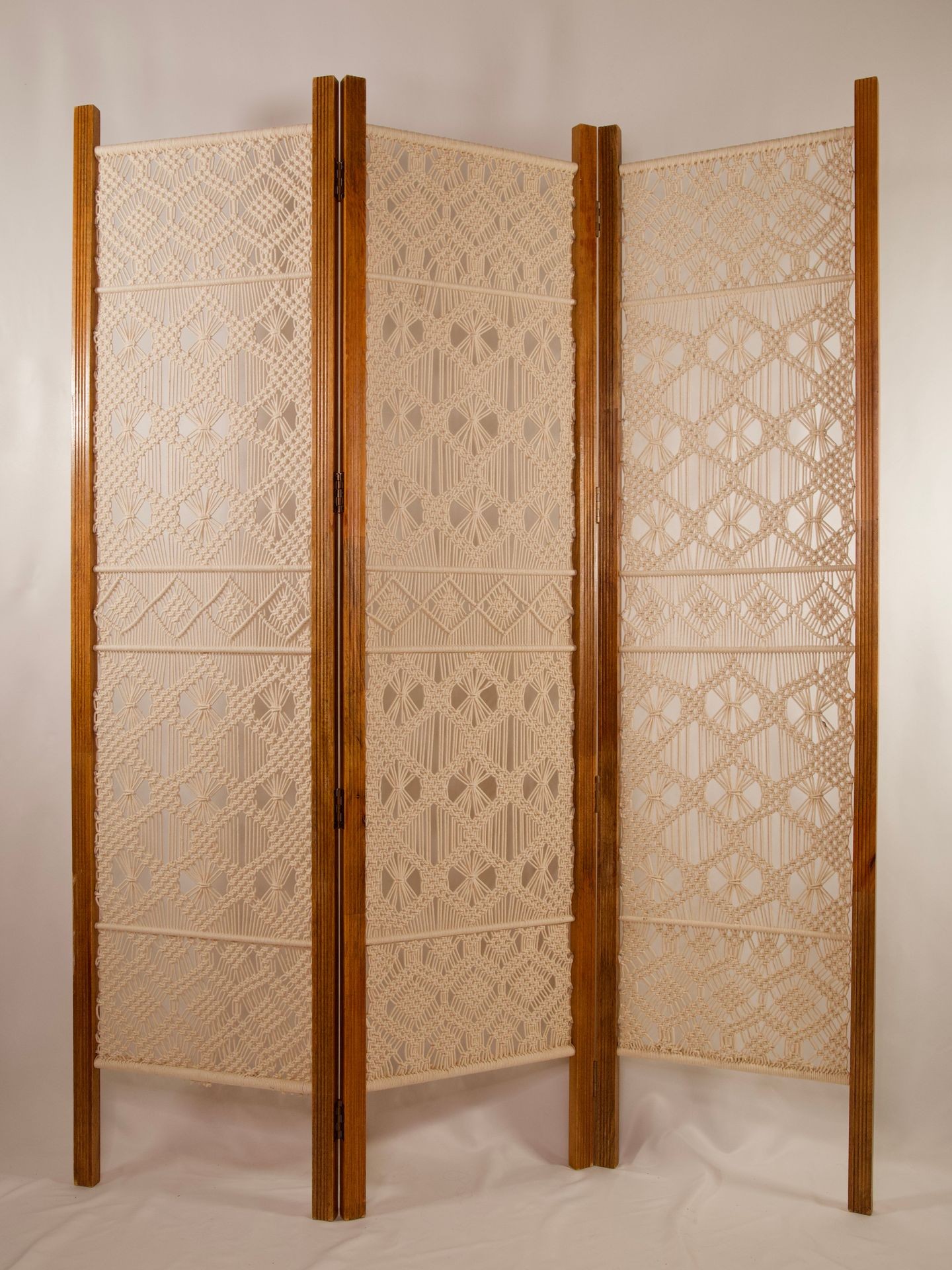 Three-panel wooden room divider featuring intricate macramé designs on each panel.