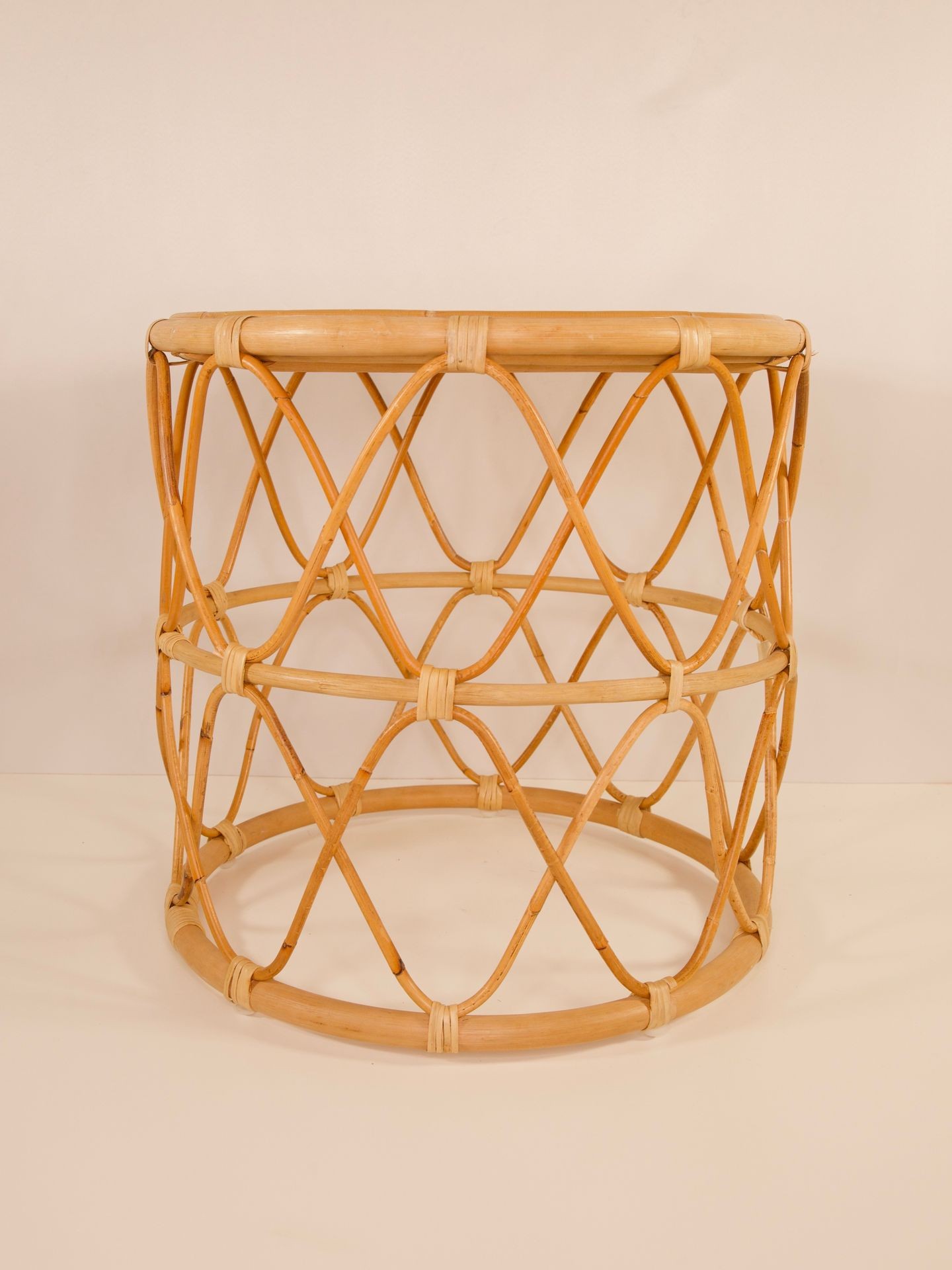 Round rattan basket with a crisscross pattern against a light background.