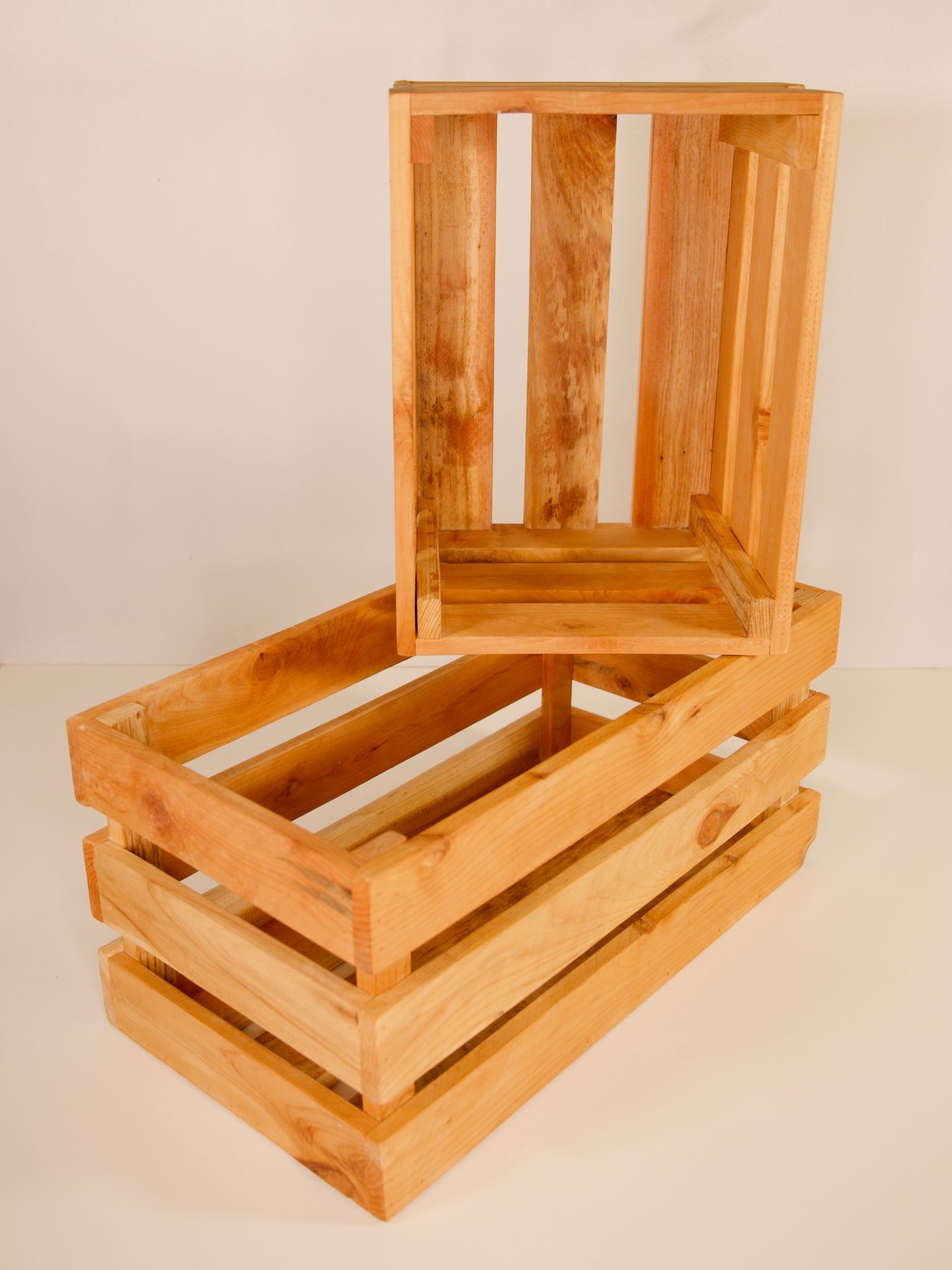 Two stacked wooden crates with a light brown finish, positioned against a plain background.