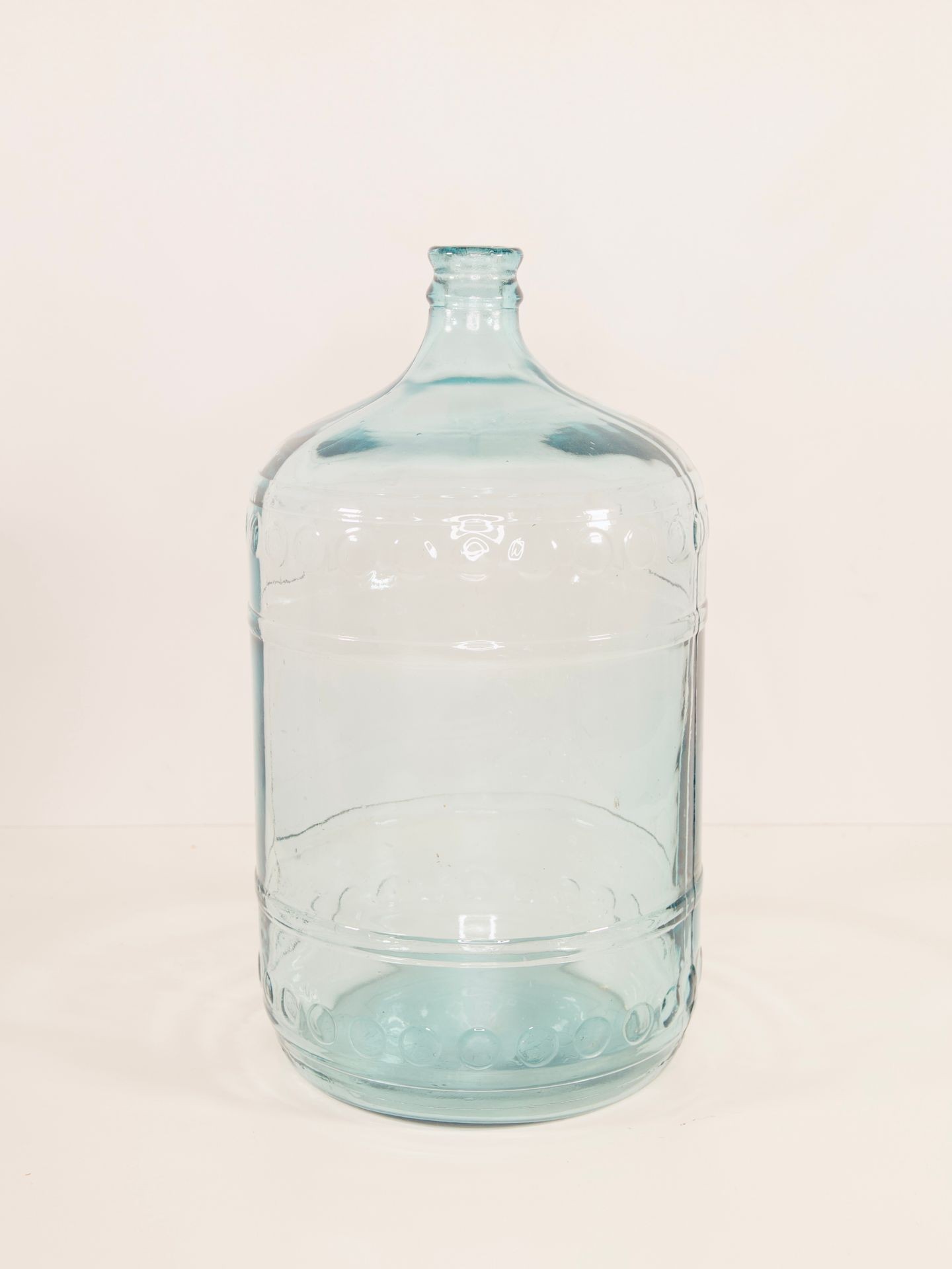 Clear glass water jug with a narrow neck and rounded body, placed on a plain white background.