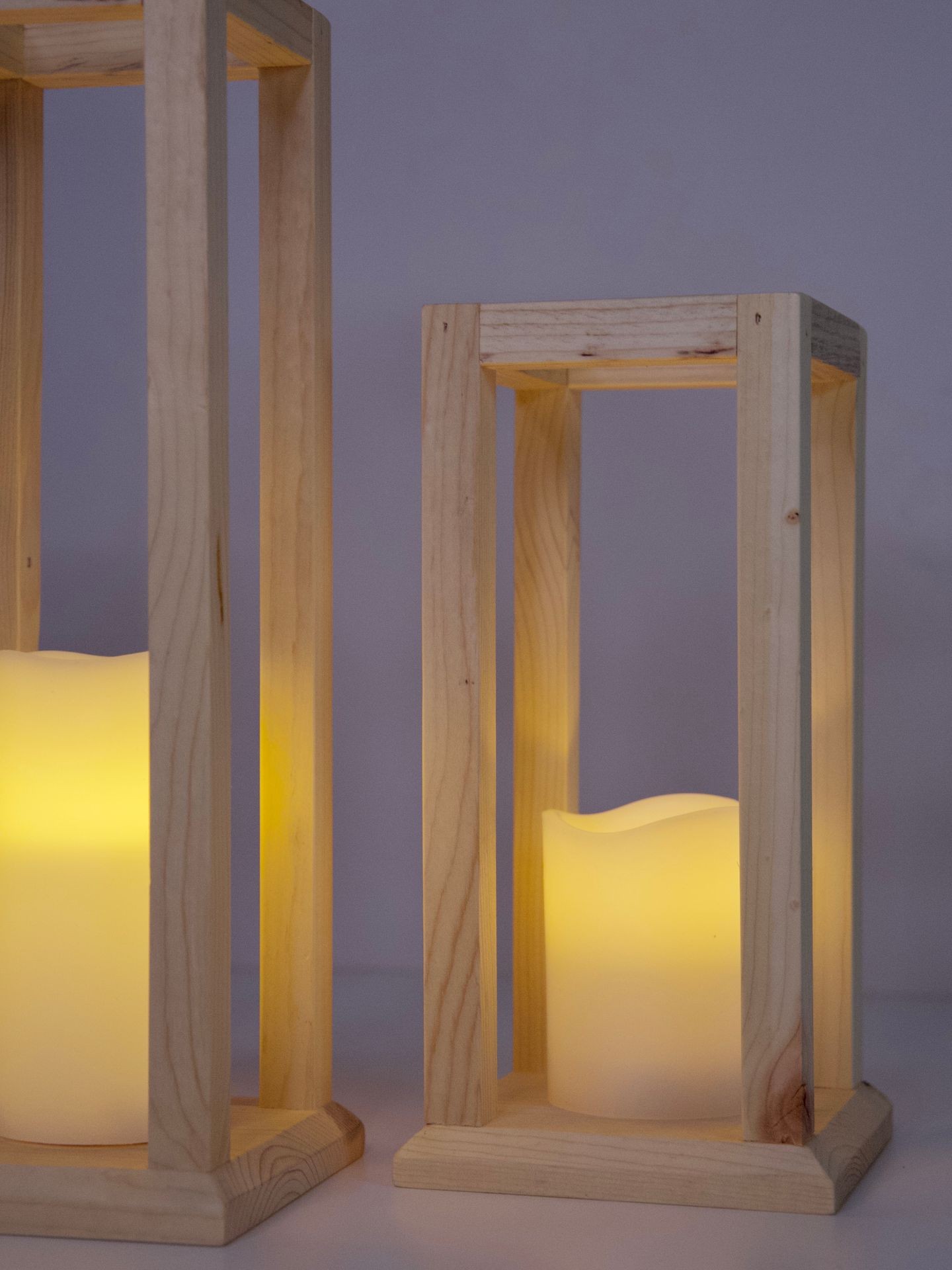 Two wooden lanterns with glowing LED candles inside, creating a warm and cozy ambiance.