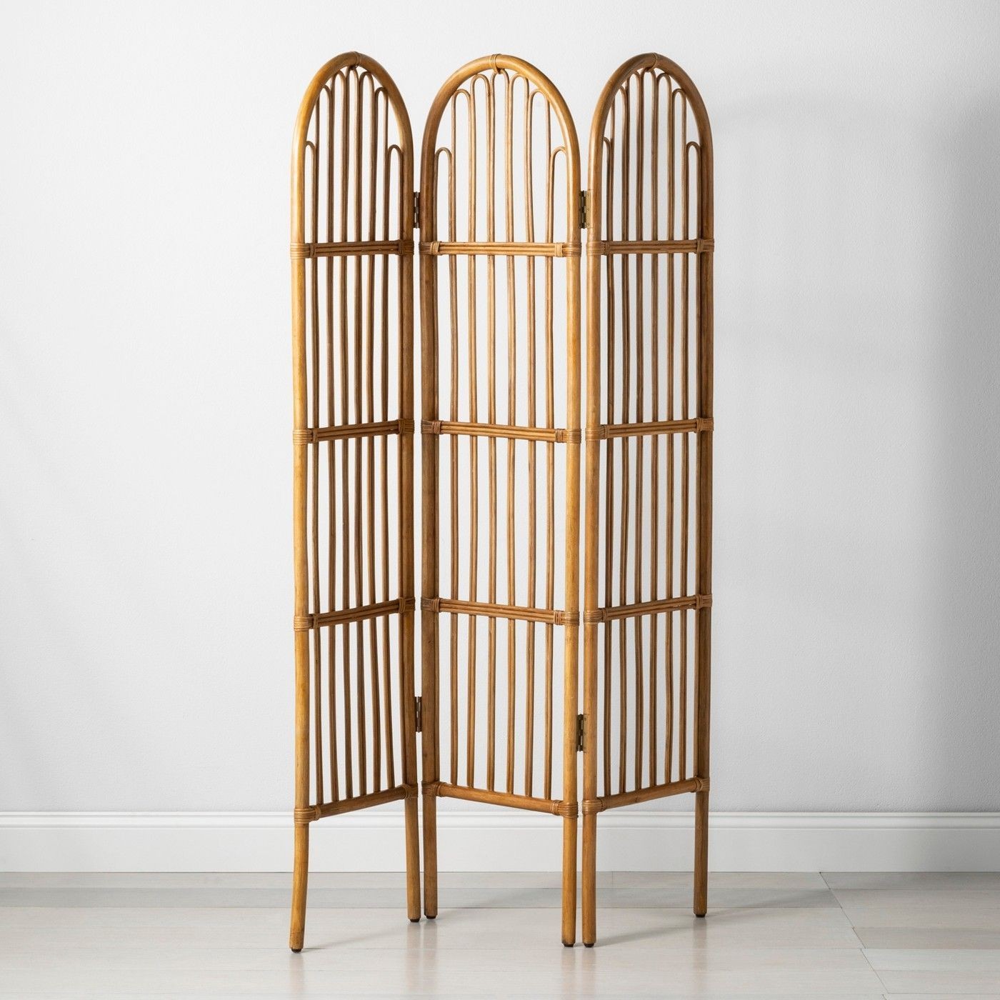 Three-panel wooden room divider with arched tops, standing against a plain white wall.