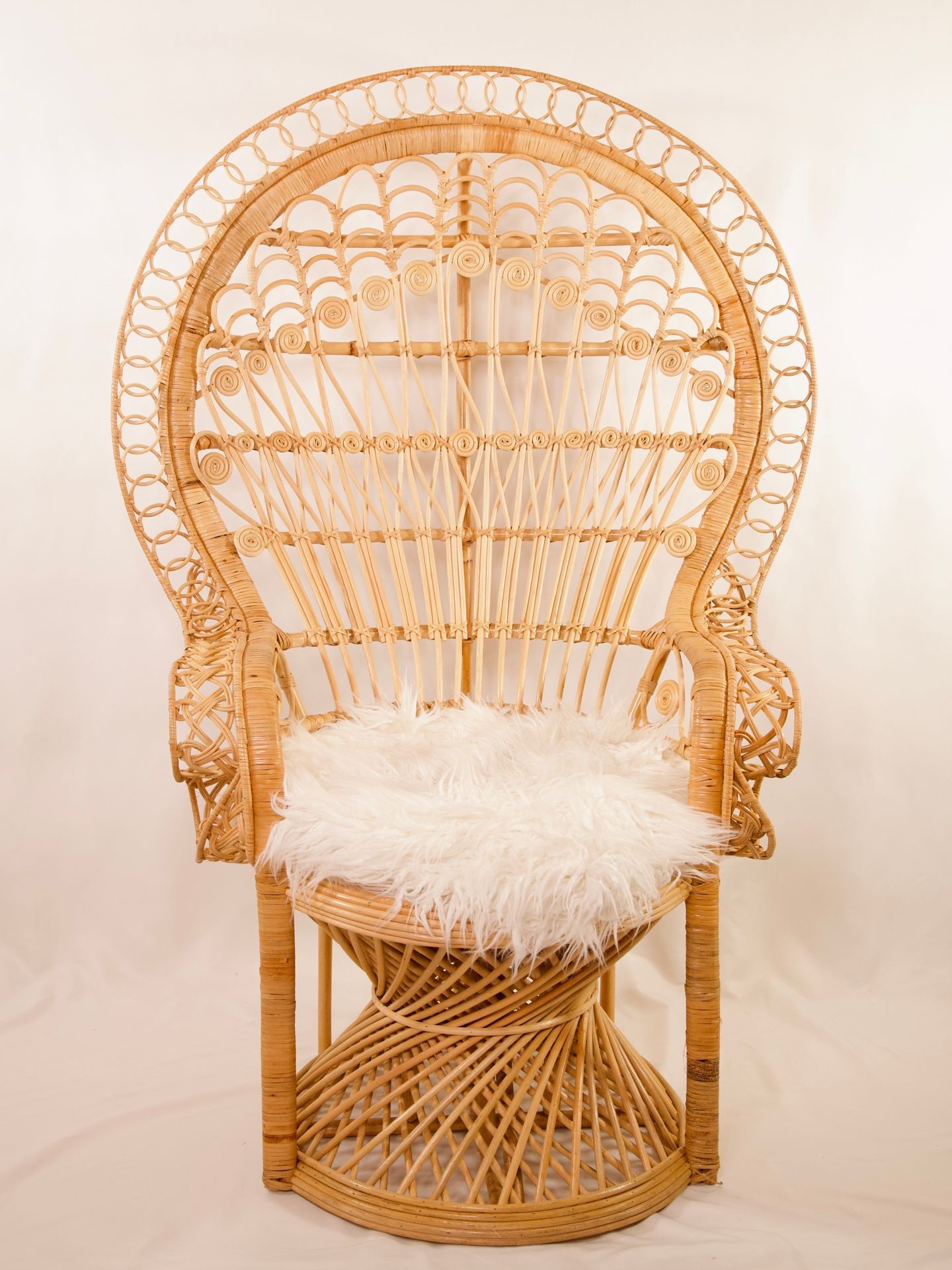 Ornate rattan chair with intricate woven design and a fluffy white cushion on the seat.