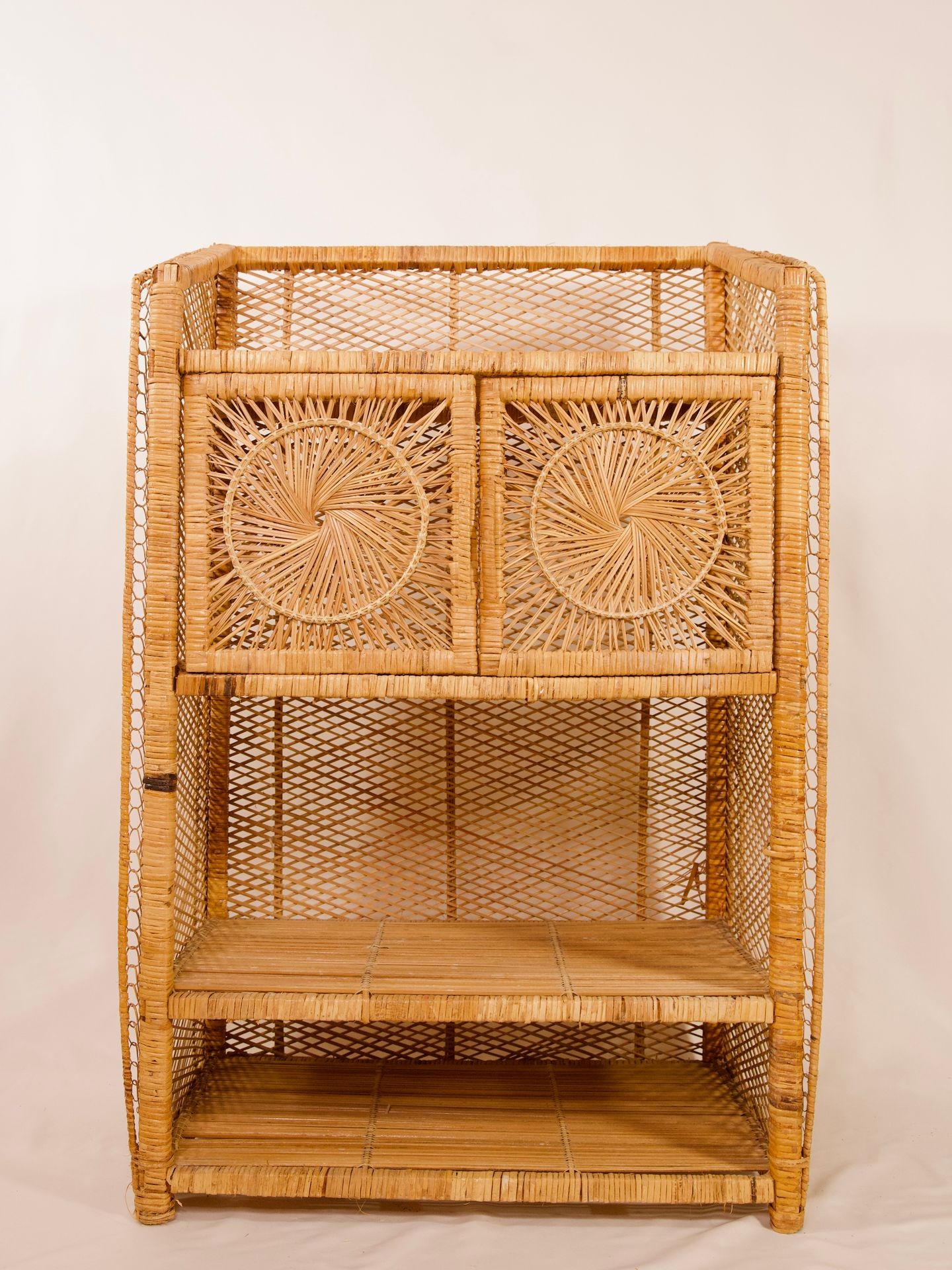 Handwoven wicker shelving unit with two small closed compartments at the top and two open shelves below.