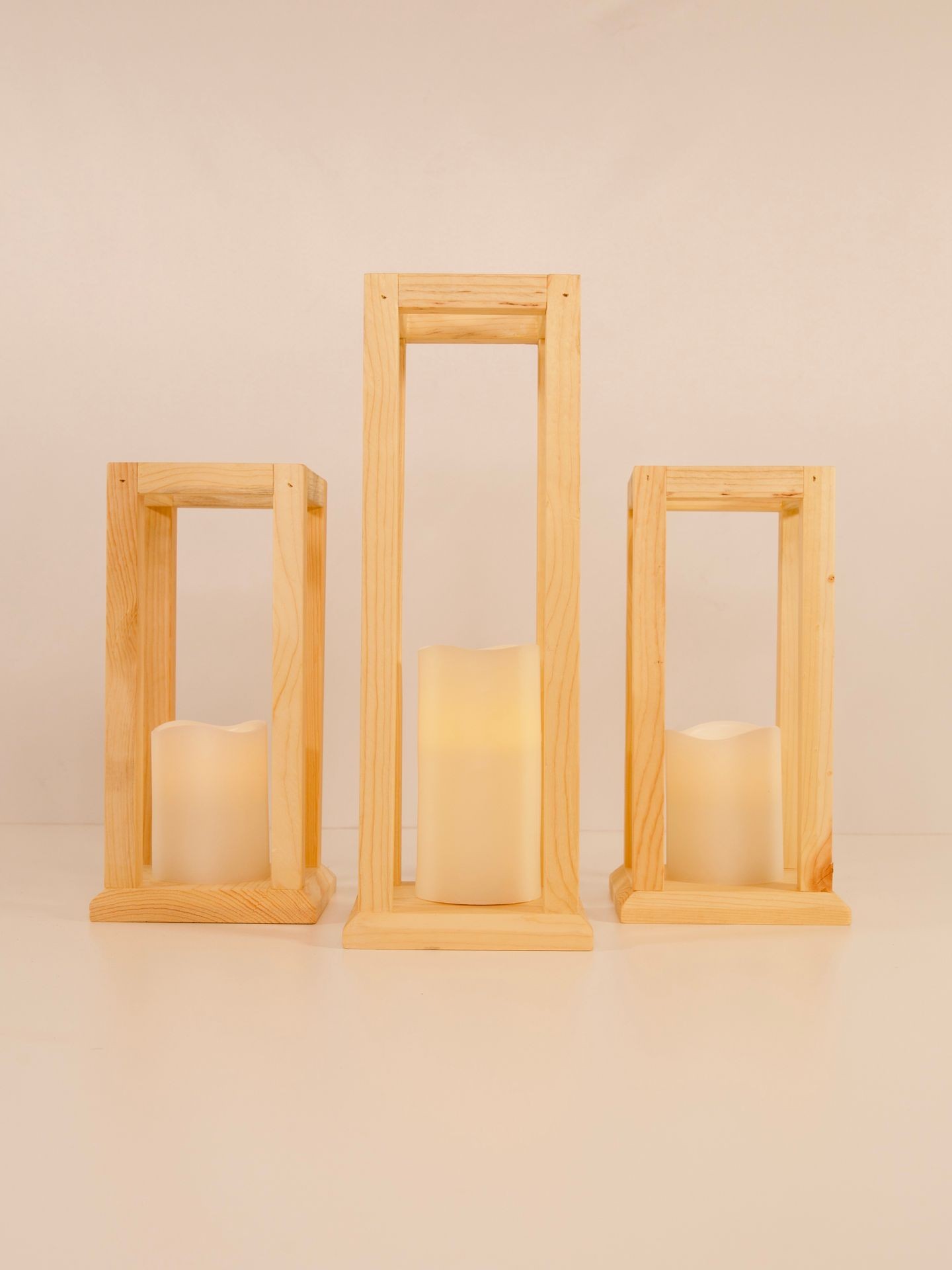 Three wooden lanterns with lit candles inside, arranged on a white background.