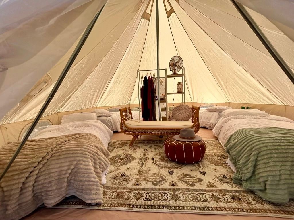 Luxurious glamping tent interior with beds, a rug, and stylish furnishings.