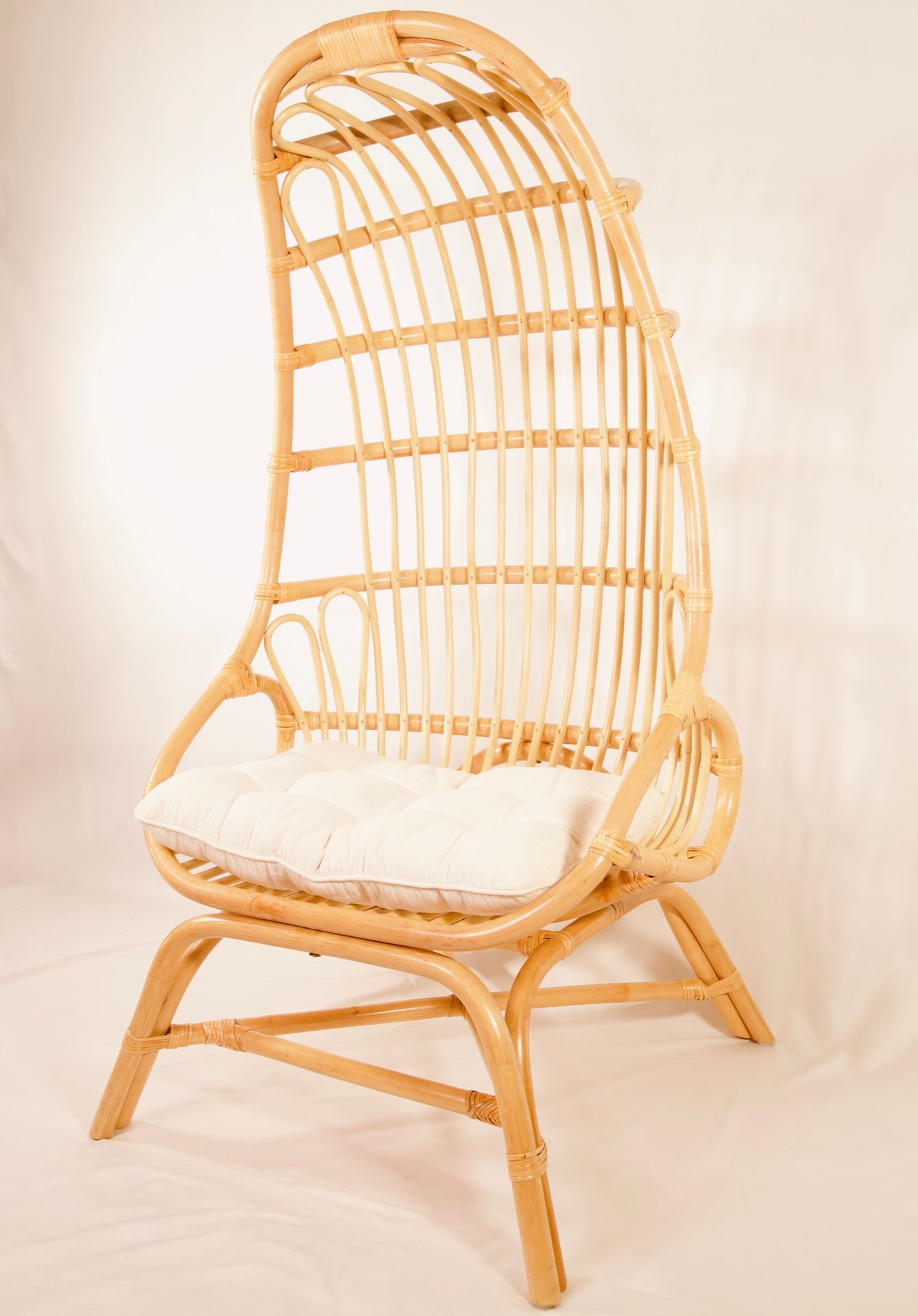 Tall wicker chair with a white cushion, featuring a high back and curved design.