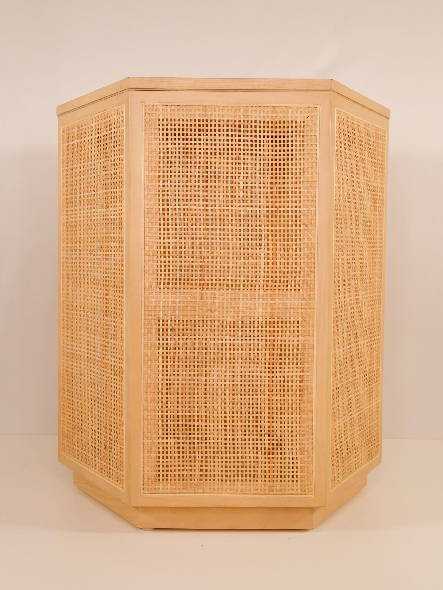 Hexagonal wooden cabinet with woven rattan panels on a light background.