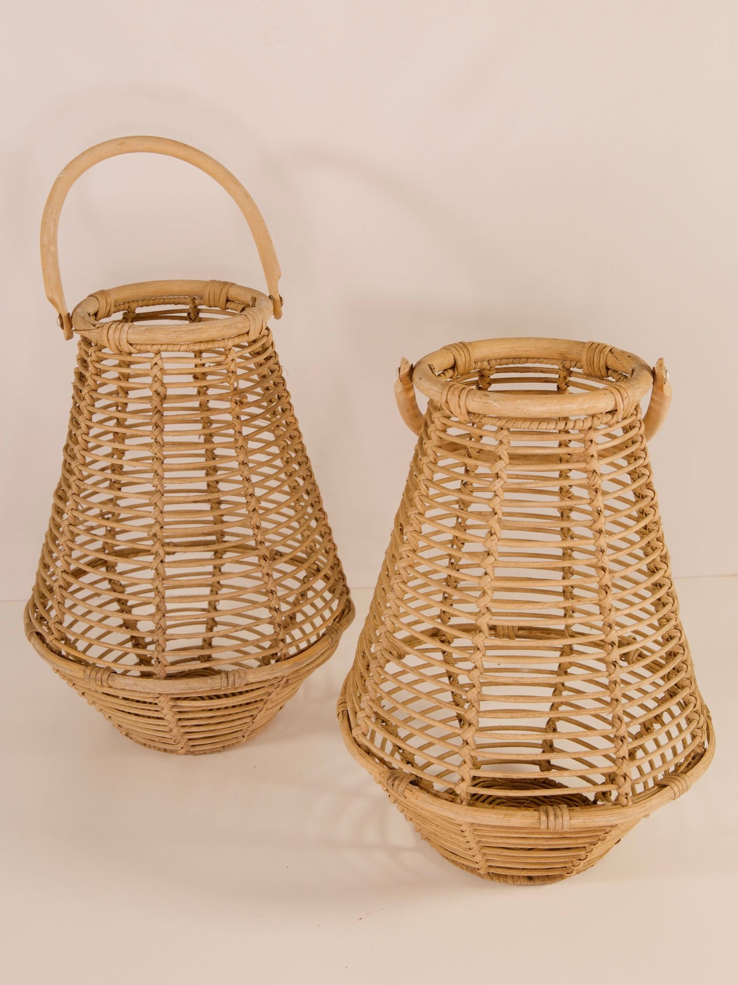 Two wicker baskets with wide bases and open weave design, one featuring a handle on top.