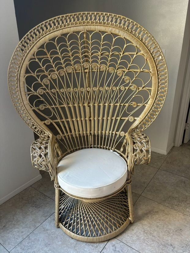 Peacock wicker chair with intricate woven design and white cushion placed on a tiled floor.